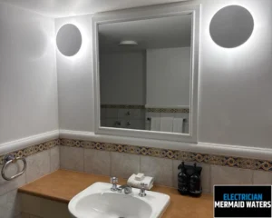 Modern bathroom with a clean, white sink, large mirror, and decorative tile accents.